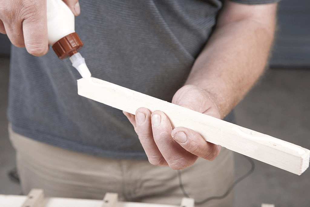 A Man is Gluing the Wooden Frame