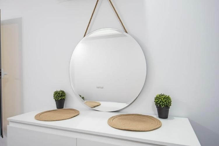 Round Shaped Frameless Mirror is Hanging Above the Table
